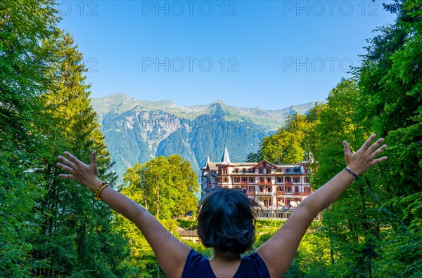 Woman with Arms Outstretched in Front of The Historical Grandhotel Giessbach on the Mountain Side in Brienz