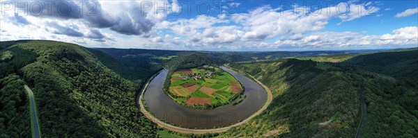 River bend of the Saar. The river winds through the valley and is surrounded by green hills and forests. Serrig