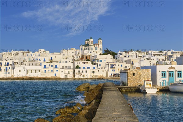 Traditional Greek whitewashed houses and church of Dormition of Mother of God as local landmark on hilltop by seafront on sunny day