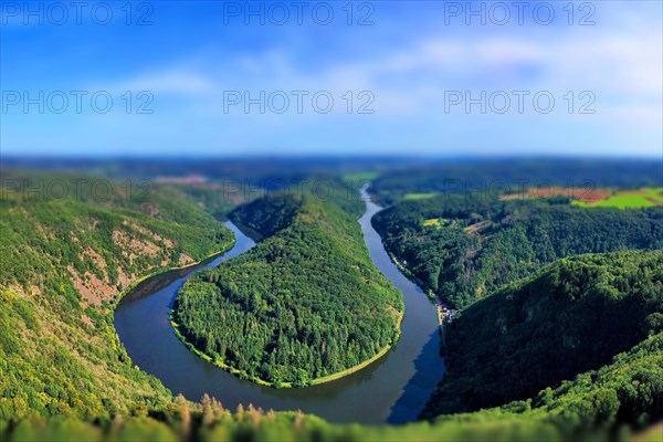 Aerial view of the Saar Loop. The Saar winds through the valley and is surrounded by green forests. Orscholz