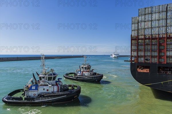 Container ship with tugboats in the harbour