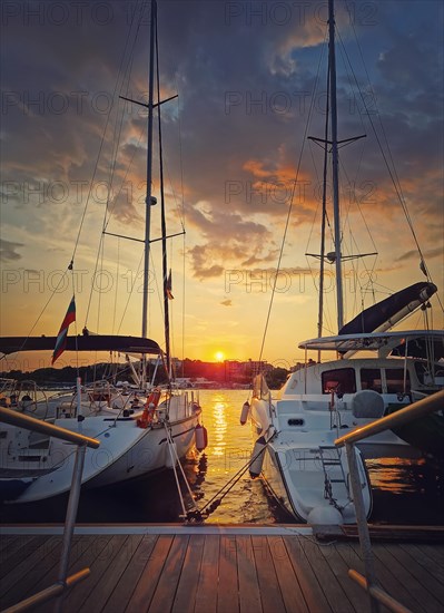 Sunset scene at the harbor as seen through the yachts moored at the pier in the old town of Nessebar