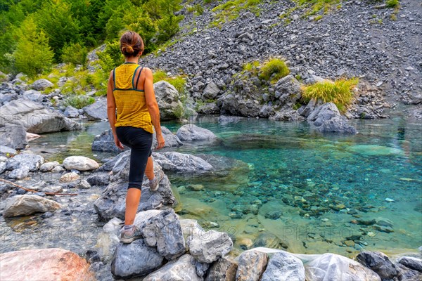 A young woman in the turquoise water reservoir in the valley of Theth national park