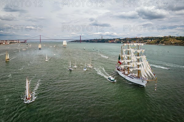 Aerial drone view of tall ships with sails sailing in Tagus river towards the Atlantic ocean in Lisbon