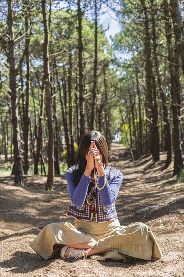 Kali mudra executed in lotus position by a woman in a forest