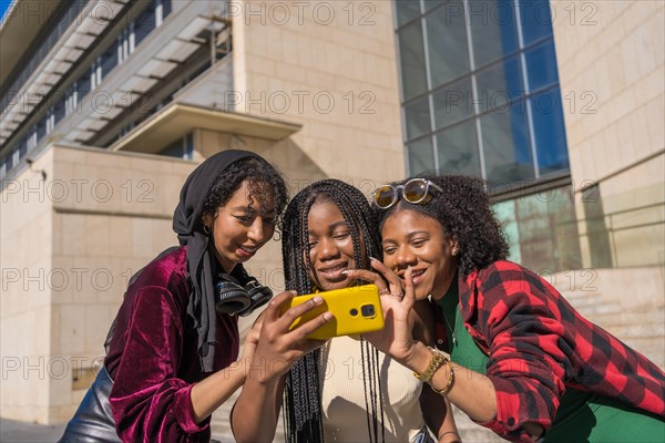 Curious multi-ethnic friends using mobile in the street in the city