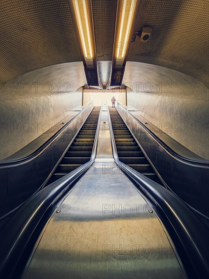 Lone man climbing out on a subway escalator. Symmetrical underground moving staircase