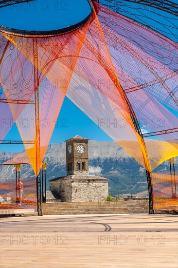 Colored arch in the Ottoman Castle Fortress of Gjirokaster or Gjirokastra and in the background the church with the clock tower. Albania