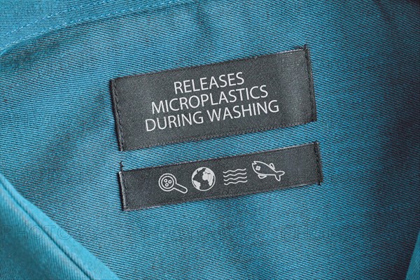 Clothing label saying 'Releases microplastics during washing'. Concept for synthetic clothing fiber pollution problem