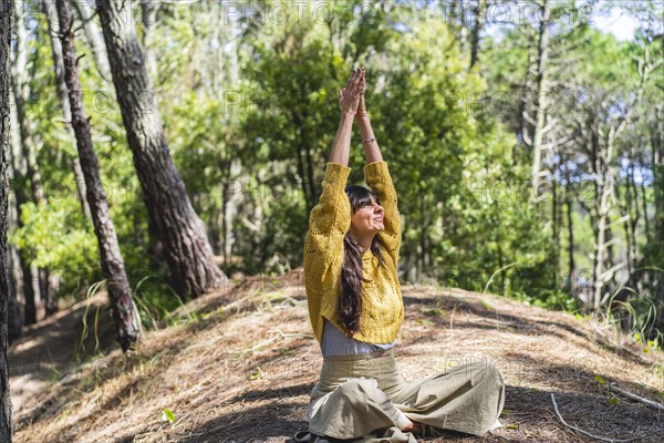 Woman about to meditate with hands clasped to the sky on the woods