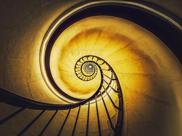 Spiral stairway abstract swirl hypnotising perspective. View downstairs to infinity circular stairs glowing in yellow light background