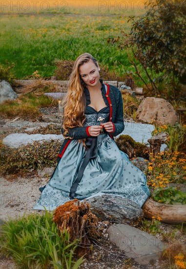 Woman in festive dirndl and flowers in hand