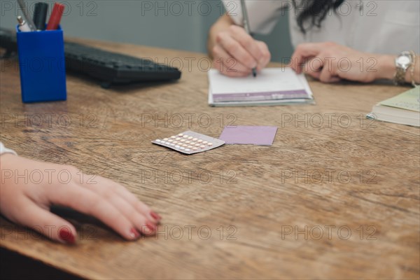 Female doctor prescribing the oral contraceptive pill to her patient. Unrecognizable persons