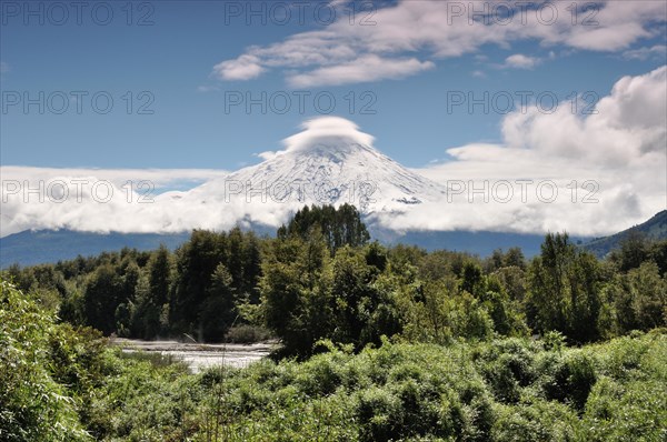 The snow-covered Osorno volcano with a storm cloud at the summit