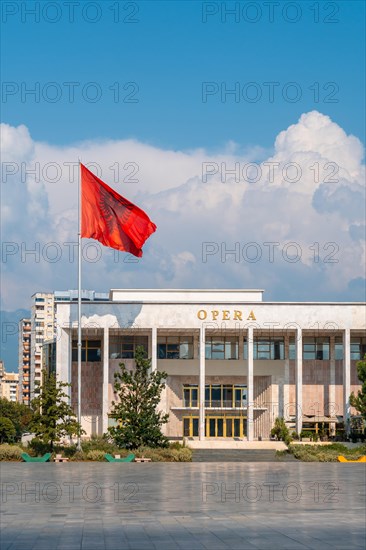 Palace of Culture or Opera on Skanderbeg Square in Tirana and the flag of Albania moving in the wind