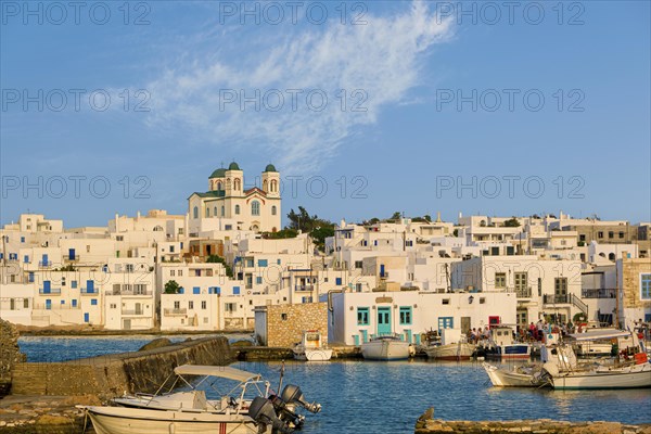 Traditional Greek whitewashed houses and church of Dormition of Mother of God as local landmark on hilltop by seafront on sunny day