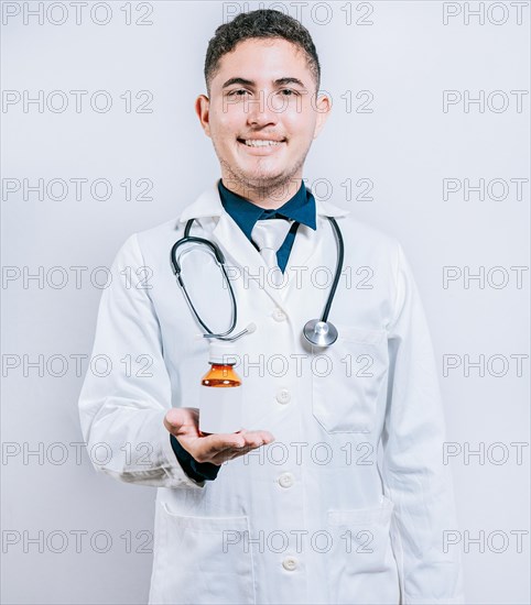 Smiling young doctor showing a bottle of syrup. Doctor showing a bottle of syrup