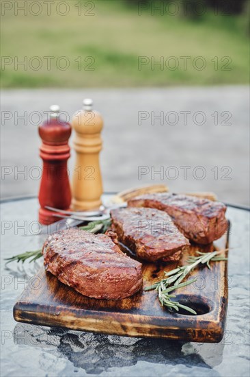 Grilled New York strip steaks on the glass table on backyard
