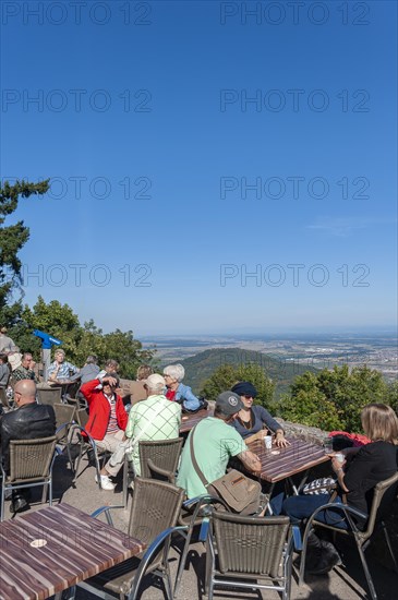 Tourists at the viewpoint in front of the Chateau du Haut Koenigsbourg. In the background the Upper Rhine Plain and the hilly landscape of the Black Forest