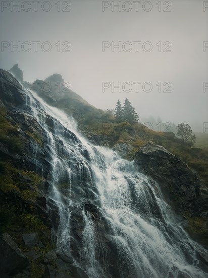 (Capra) waterfall on the Transfagarasan winding route of Carpathian mountains, Romania. Wonderful landscape with a tumultuous river flowing down through the cliffs in a foggy autumn morning