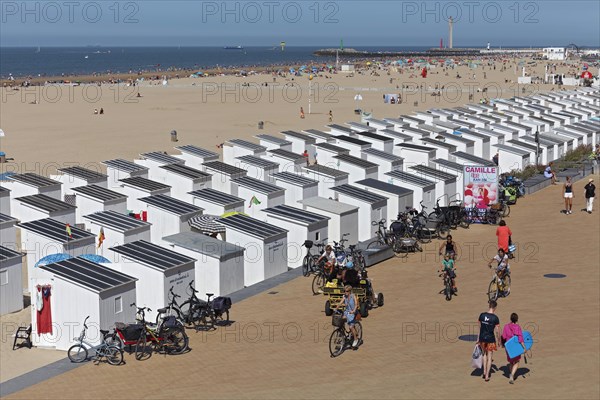 Beach with white beach huts and promenade in summer