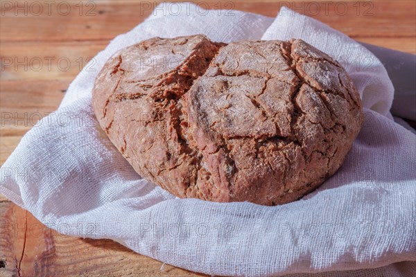 Loaf of rustic village bread on a wooden table with flour