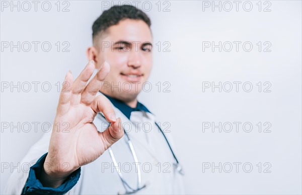 Cheerful doctor gesturing approval isolated. Handsome latin doctor approving and recommending isolated