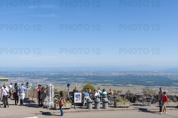 Tourists at the viewpoint in front of the Chateau du Haut Koenigsbourg. In the background the Upper Rhine Plain and the hilly landscape of the Black Forest