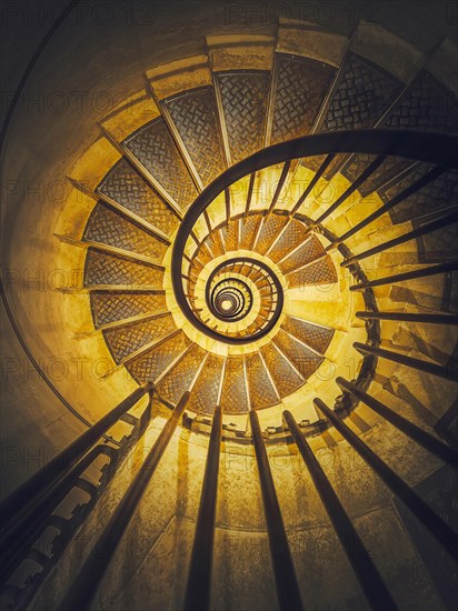 Spiral staircase abstract perspective with view downstairs to infinity swirl stairs in glowing yellow light