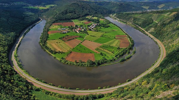 River bend of the Saar. The river winds through the valley and is surrounded by green hills and forests. Serrig