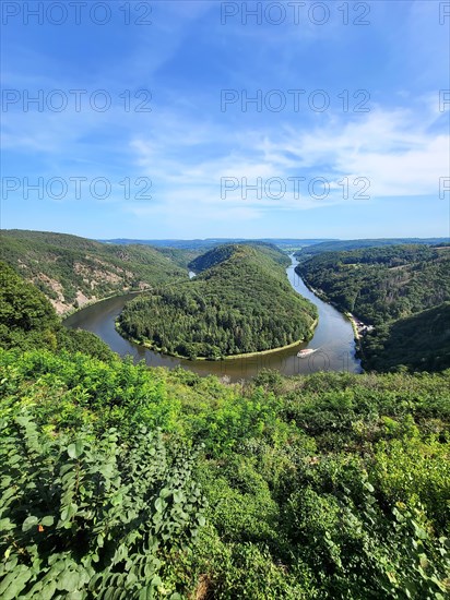 Aerial view of the Saar Loop. The Saar winds through the valley and is surrounded by green forests. Orscholz