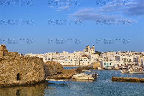 Traditional Greek whitewashed houses and church of Dormition of Mother of God as local landmark on hilltop by seafront on sunny day