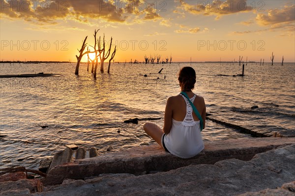 Woman contemplating the sunset in front of the sea