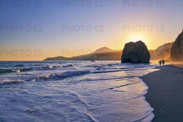 Distant silhouettes of two adults walking in tidal waters on Fyriplaka beach