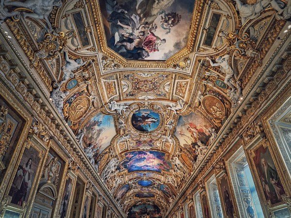 The Galerie d'Apollon a large and iconic room of the Louvre museum. Apollon gallery is a gold decorated hall with zodiac signs ornaments and murals on the walls and ceiling. Architectural masterpiece