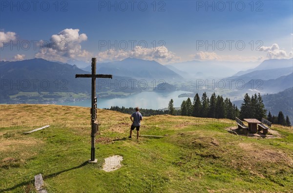 Wandersr at the summit cross of the Breitenberg with view to the Wolfgangsee