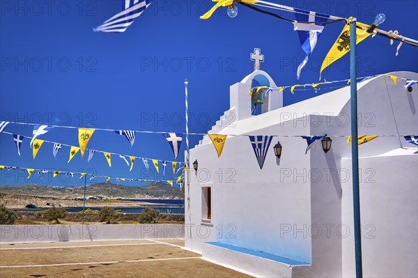 White Greek Orthodox chapel or church on top of hill decorated Greek national