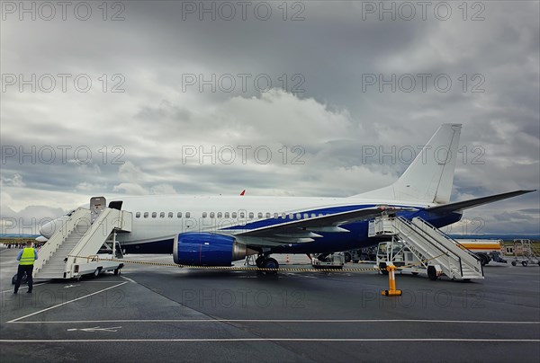 Plane ready for boarding at airport in a cloudy day. Passenger transportation at Charles de Gaulle Airport in Paris. Travel and industry concepts