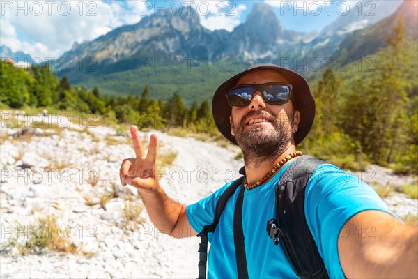 Selfie of a male hiker walking in the Valbona valley next to trees