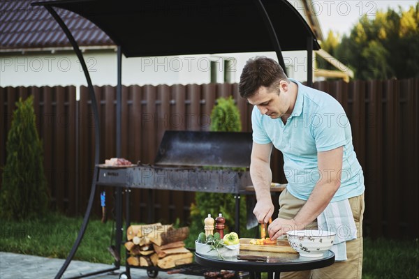 Man makes vegetable salad on backyard