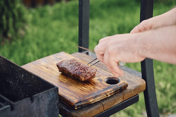 Unrecognizable man takes out juicy club steak from grill