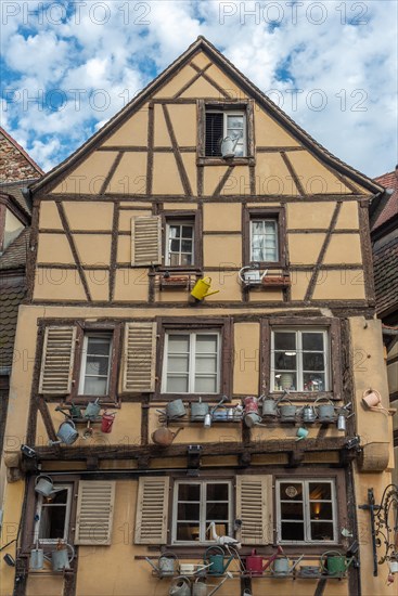 Facade of a traditional Alsatian house decorated with old water jugs