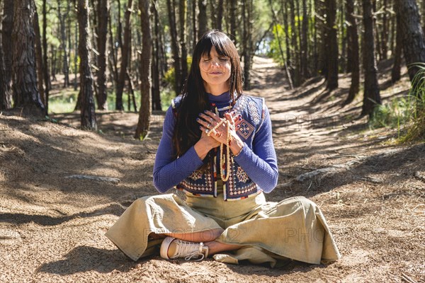 Portrait of an adult woman meditating with folded hands on her chest