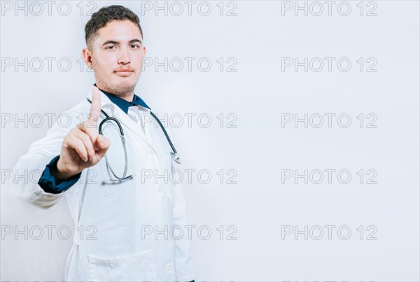 Doctor counting number ONE isolated. Handsome doctor counting number 1 on isolated background. Young doctor raising index finger isolated