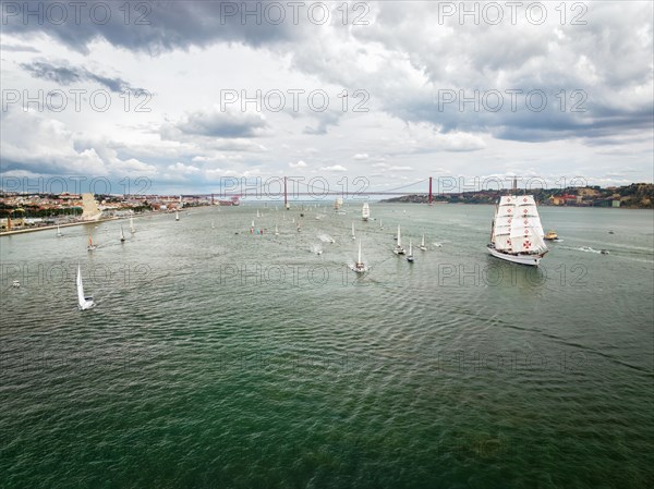 Aerial drone view of tall ships with sails sailing in Tagus river towards the Atlantic ocean in Lisbon