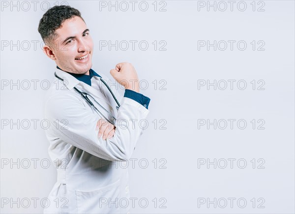 Doctor showing muscle and smiling isolated. Young doctor showing strength with his arm