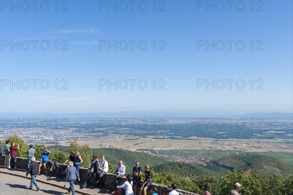Tourists at the viewpoint in front of the Chateau du Haut Koenigsbourg. In the background the Upper Rhine Plain and the hilly landscape of the Black Forest