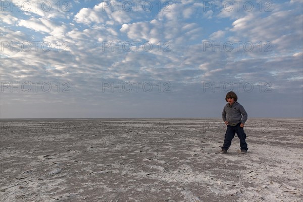 Boy running through salt desert