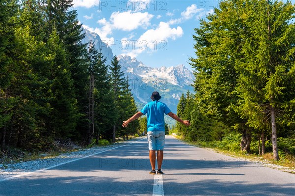 A tourist in summer walking on the road in the Valbona valley enjoying the freedom