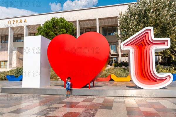 Portrait of a child in the I Love Tirana sculpture at Skanderbeg Square in Tirana reflected. Albania